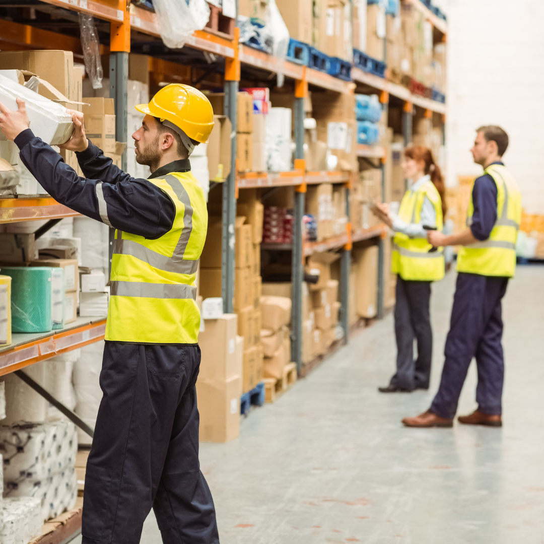 Warehouse with three workers looking at the goods